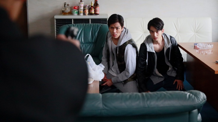 二人の若者が話を聞く場面